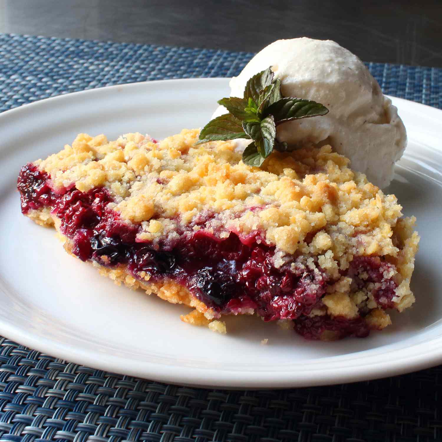 Frozen berry mix pie with a scoop of ice cream on a white plate